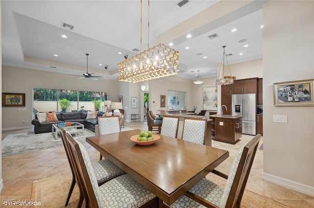 dining room with sink, ceiling fan with notable chandelier, and ornamental molding