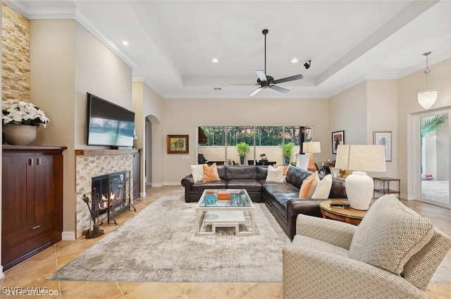 4908 Rustic Oaks Cir, Naples, FL 34105 - living area with a tray ceiling, arched walkways, a tile fireplace, a ceiling fan, and ornamental molding