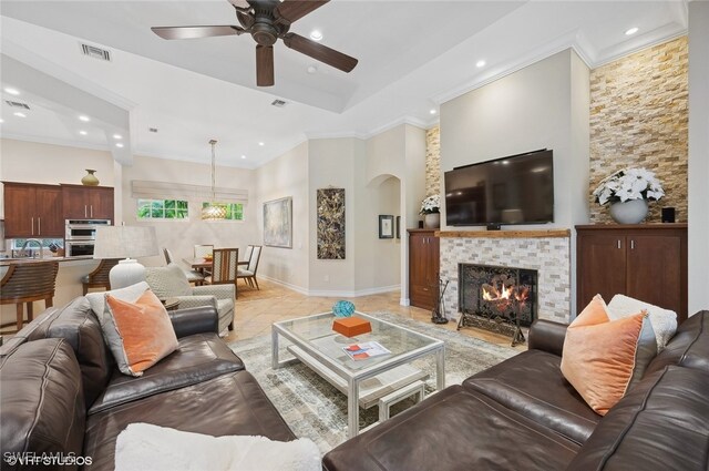 living room with ceiling fan, crown molding, and a tile fireplace