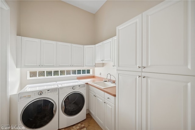 clothes washing area with washing machine and clothes dryer, cabinets, and sink