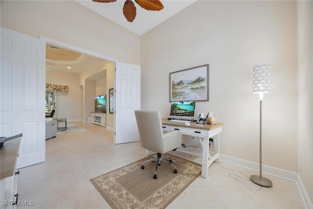 office space featuring a high ceiling, light tile patterned floors, and ceiling fan