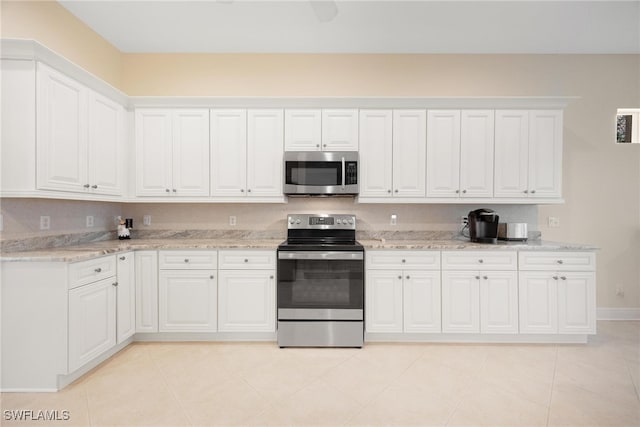 kitchen featuring light stone countertops, white cabinetry, light tile patterned floors, and stainless steel appliances