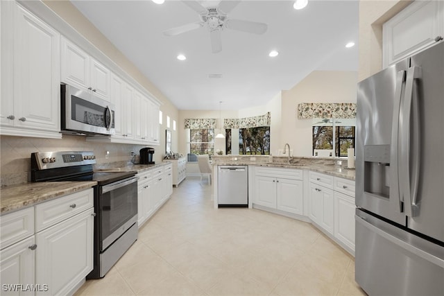 kitchen with sink, backsplash, pendant lighting, white cabinets, and appliances with stainless steel finishes