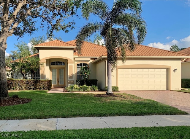 mediterranean / spanish house featuring a garage, a front lawn, and french doors