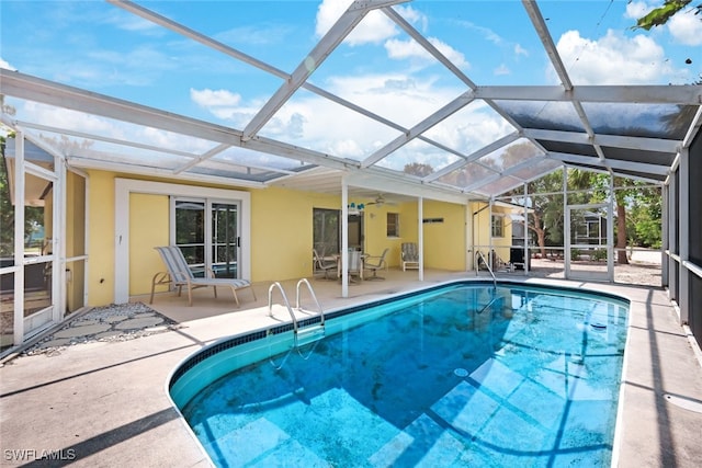 view of pool featuring ceiling fan, glass enclosure, and a patio area