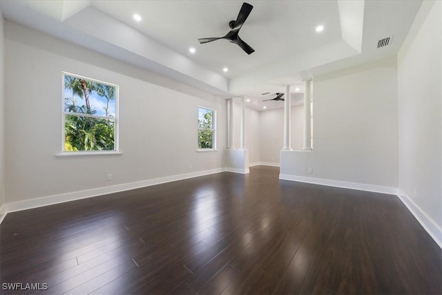 unfurnished room featuring dark wood-type flooring, ceiling fan, and a raised ceiling