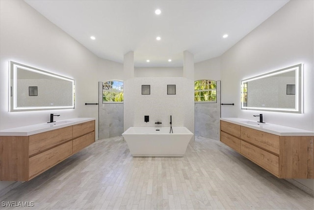 bathroom with vanity, a bathtub, lofted ceiling, and hardwood / wood-style floors