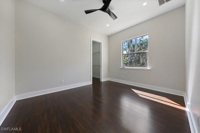 unfurnished bedroom with a spacious closet, dark wood-type flooring, a closet, and ceiling fan