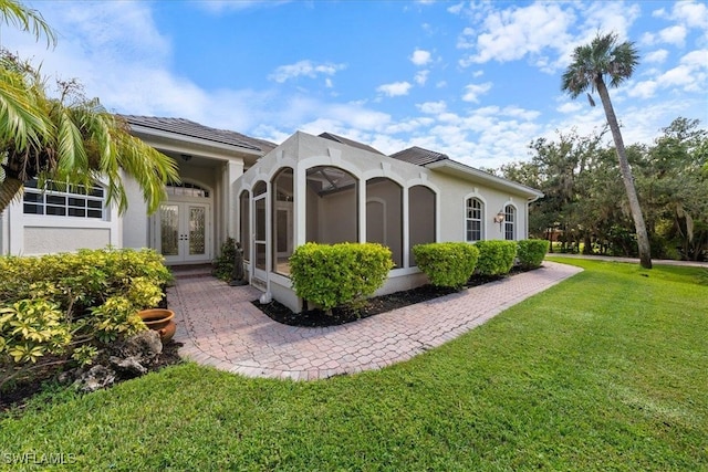 back of property featuring french doors and a lawn