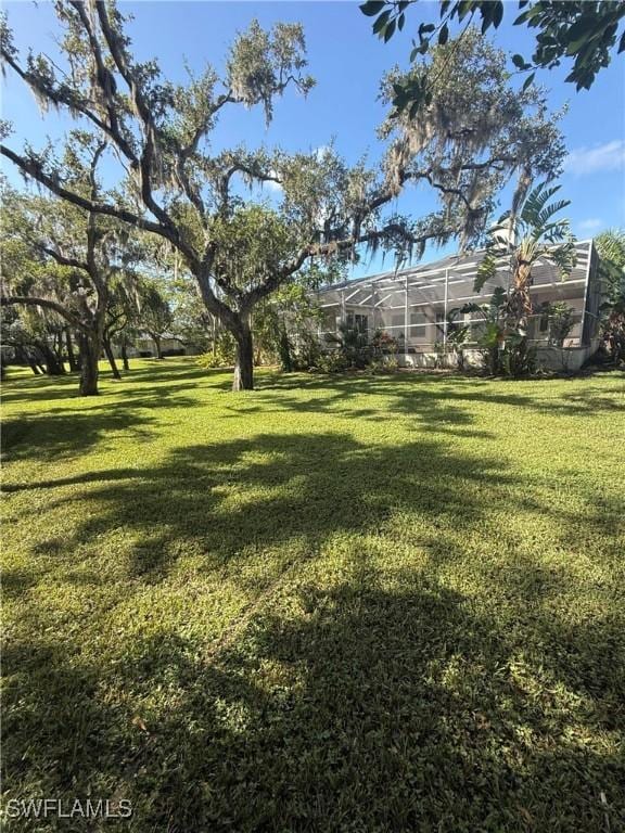 12800 Treeline Ct, North Fort Myers, FL 33903 - view of grassy yard with glass enclosure