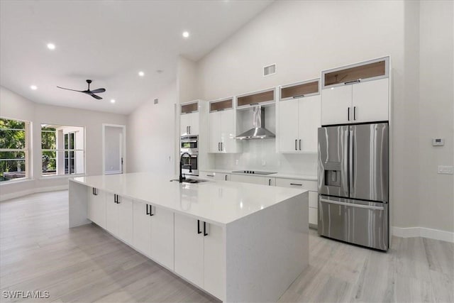 12800 Treeline Ct, North Fort Myers, FL 33903 - kitchen featuring stainless steel appliances, wall chimney exhaust hood, light wood-style flooring, a ceiling fan, and white cabinetry