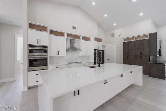 12800 Treeline Ct, North Fort Myers, FL 33903 - kitchen with wall chimney range hood, high vaulted ceiling, stainless steel appliances, white cabinetry, and a spacious island
