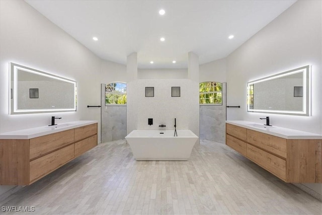 12800 Treeline Ct, North Fort Myers, FL 33903 - bathroom featuring healthy amount of natural light, two vanities, a freestanding bath, and recessed lighting