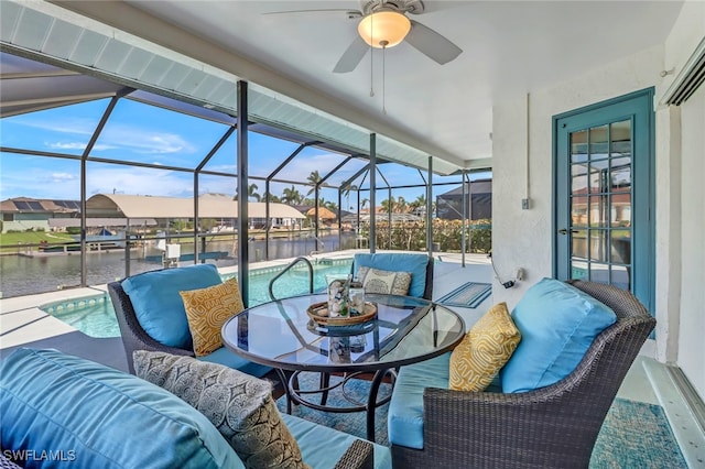 view of patio with ceiling fan, a water view, and glass enclosure