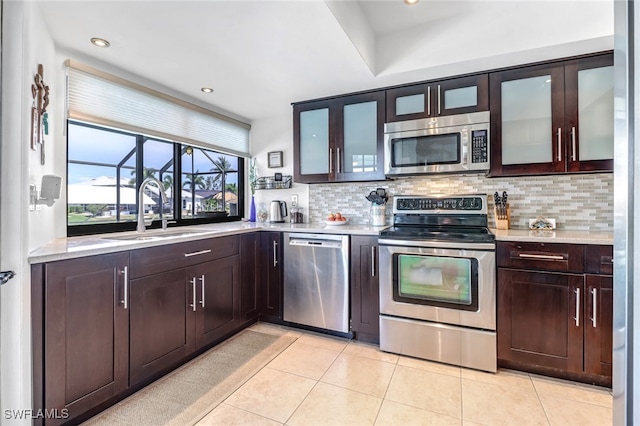 kitchen featuring light tile patterned flooring, appliances with stainless steel finishes, sink, and backsplash