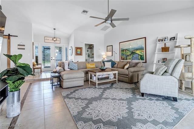 living room featuring light tile patterned flooring, french doors, high vaulted ceiling, ceiling fan, and a barn door