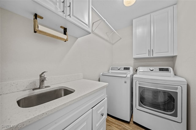 washroom featuring washer and dryer, cabinets, light wood-type flooring, and sink