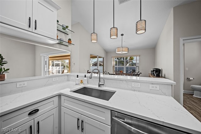 kitchen featuring vaulted ceiling, sink, dishwasher, white cabinets, and hanging light fixtures