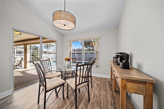 dining area featuring hardwood / wood-style flooring and vaulted ceiling