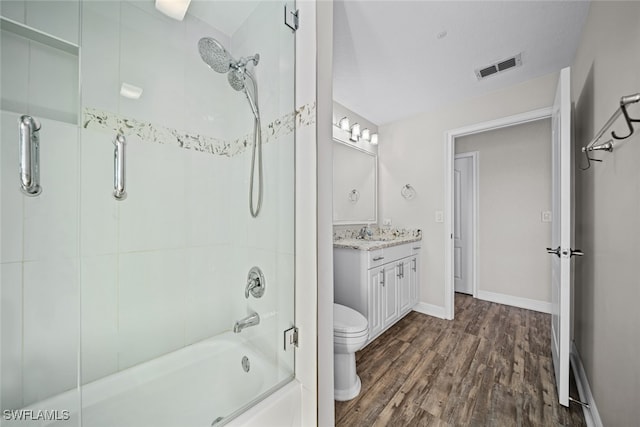 full bathroom with hardwood / wood-style flooring, vanity, toilet, and bath / shower combo with glass door