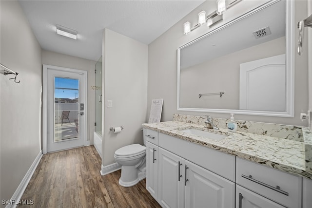 full bathroom featuring washtub / shower combination, hardwood / wood-style floors, vanity, and toilet