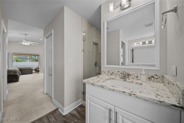 bathroom featuring a shower with shower door, ceiling fan, wood-type flooring, and vanity