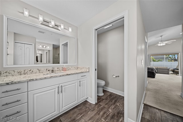 bathroom with hardwood / wood-style floors, vanity, toilet, and ceiling fan