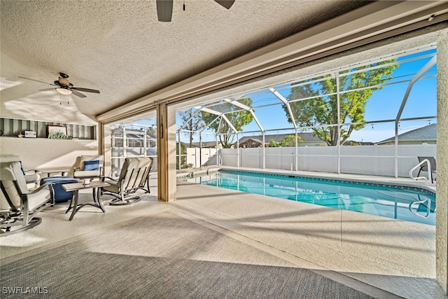 view of swimming pool with glass enclosure, ceiling fan, and a patio area