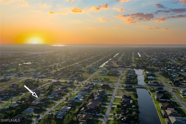 aerial view at dusk featuring a water view