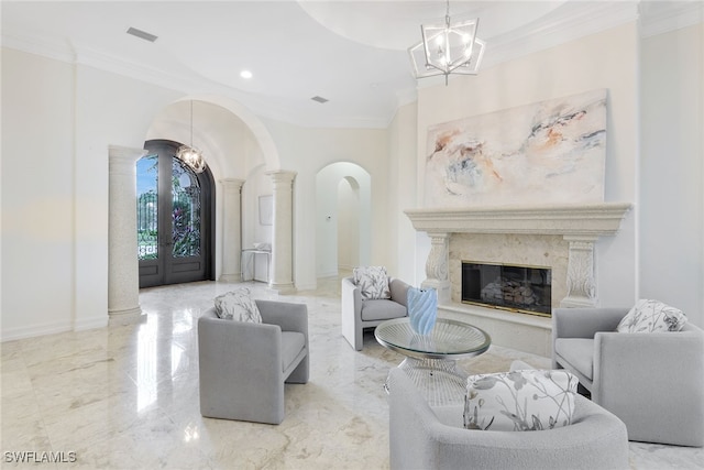 living room featuring decorative columns, an inviting chandelier, a premium fireplace, and crown molding