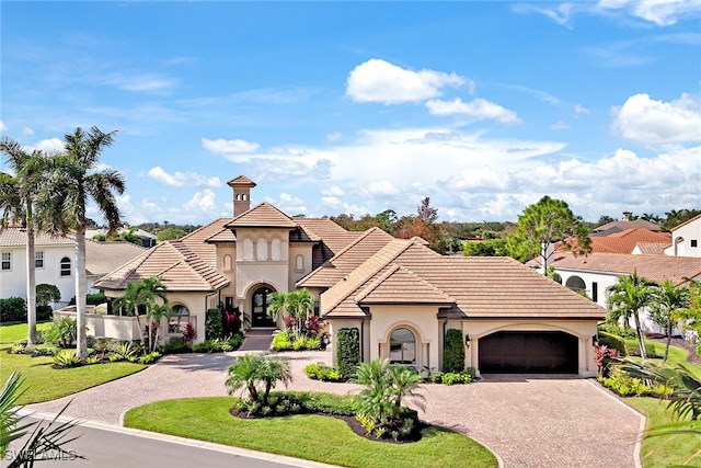 mediterranean / spanish-style house featuring a garage and a front lawn