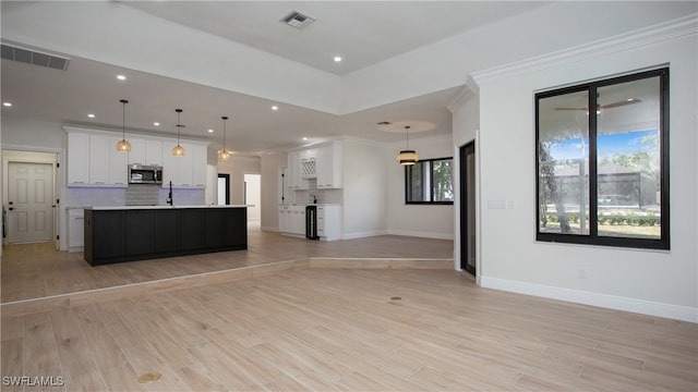 kitchen with a spacious island, light hardwood / wood-style flooring, backsplash, pendant lighting, and white cabinets