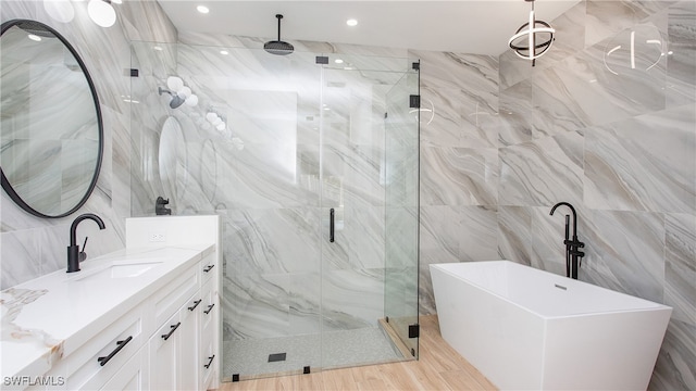 bathroom featuring vanity, hardwood / wood-style flooring, tile walls, and separate shower and tub