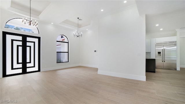 foyer featuring crown molding, light hardwood / wood-style flooring, an inviting chandelier, and a raised ceiling