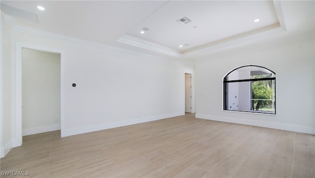 unfurnished room featuring ornamental molding, a tray ceiling, and light wood-type flooring