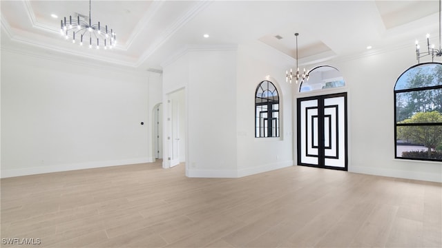 foyer featuring light hardwood / wood-style flooring, a notable chandelier, a tray ceiling, and crown molding