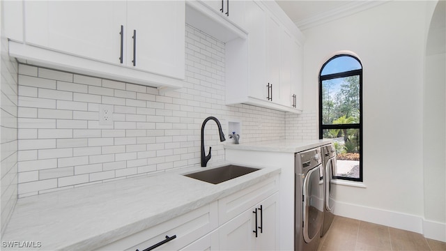 clothes washing area with light hardwood / wood-style flooring, crown molding, sink, cabinets, and washing machine and clothes dryer