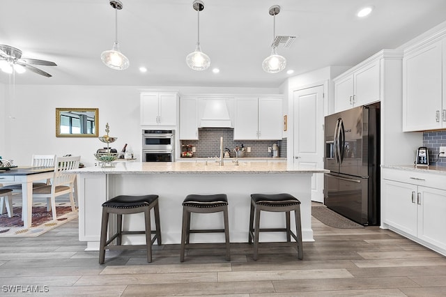 kitchen with white cabinets, refrigerator with ice dispenser, and stainless steel double oven