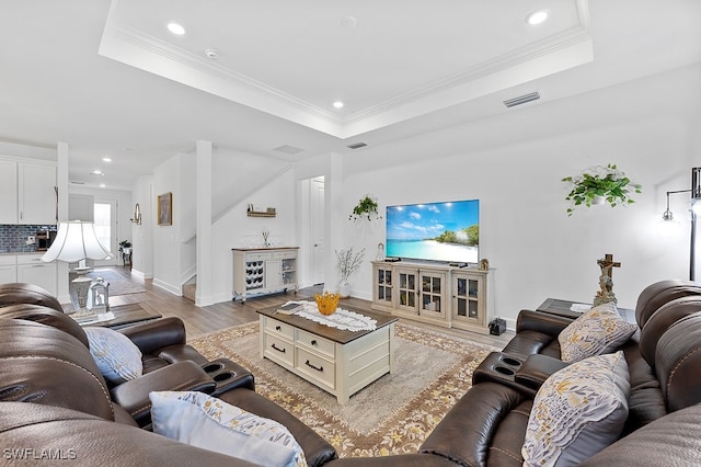 living room featuring light hardwood / wood-style floors, crown molding, and a tray ceiling