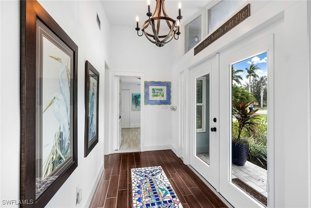 doorway with a towering ceiling, an inviting chandelier, and dark hardwood / wood-style flooring