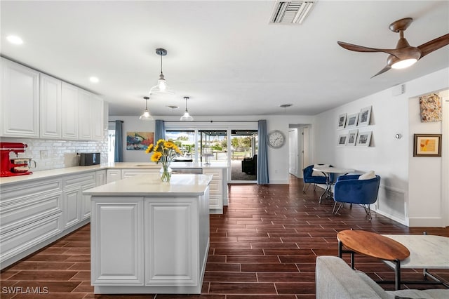 kitchen featuring decorative backsplash, white cabinets, hanging light fixtures, and dark hardwood / wood-style floors