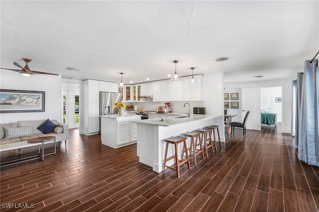 kitchen with a center island with sink, sink, pendant lighting, appliances with stainless steel finishes, and dark hardwood / wood-style flooring