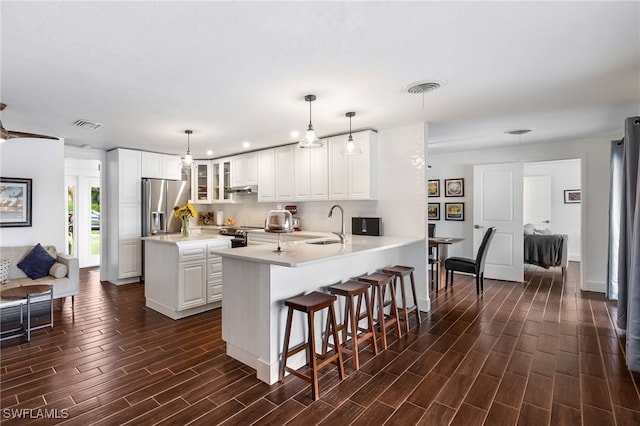 kitchen featuring dark hardwood / wood-style floors, kitchen peninsula, stainless steel appliances, decorative light fixtures, and white cabinetry