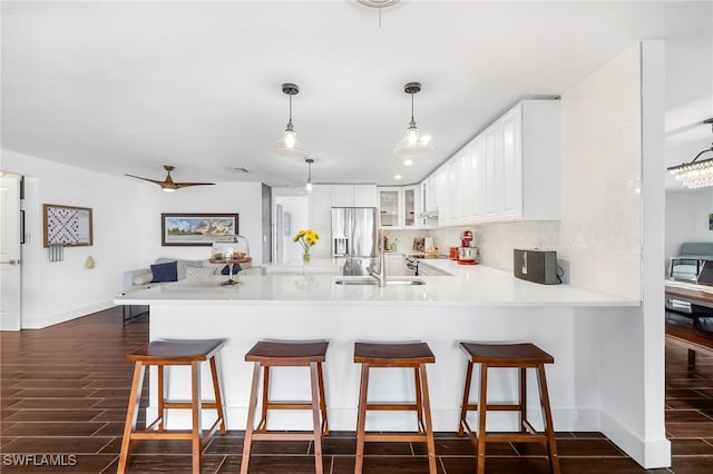 kitchen featuring stainless steel fridge, dark hardwood / wood-style flooring, kitchen peninsula, and white cabinets