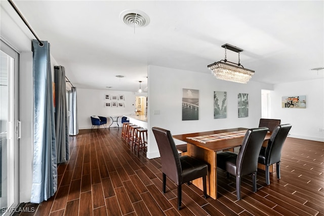 dining space with dark wood-type flooring and an inviting chandelier