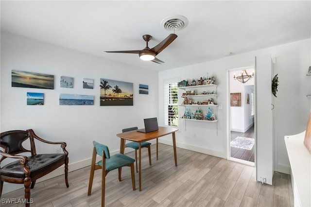 office with ceiling fan with notable chandelier and light wood-type flooring