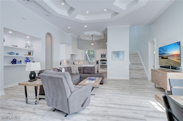 living room with a high ceiling, light wood-type flooring, crown molding, and coffered ceiling