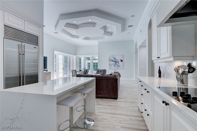 kitchen featuring stainless steel built in fridge, white cabinetry, light wood-type flooring, and coffered ceiling