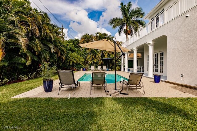 view of swimming pool featuring french doors, a patio, ceiling fan, and a lawn