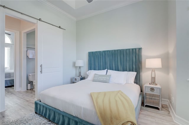 bedroom featuring a barn door, light wood-type flooring, and ornamental molding